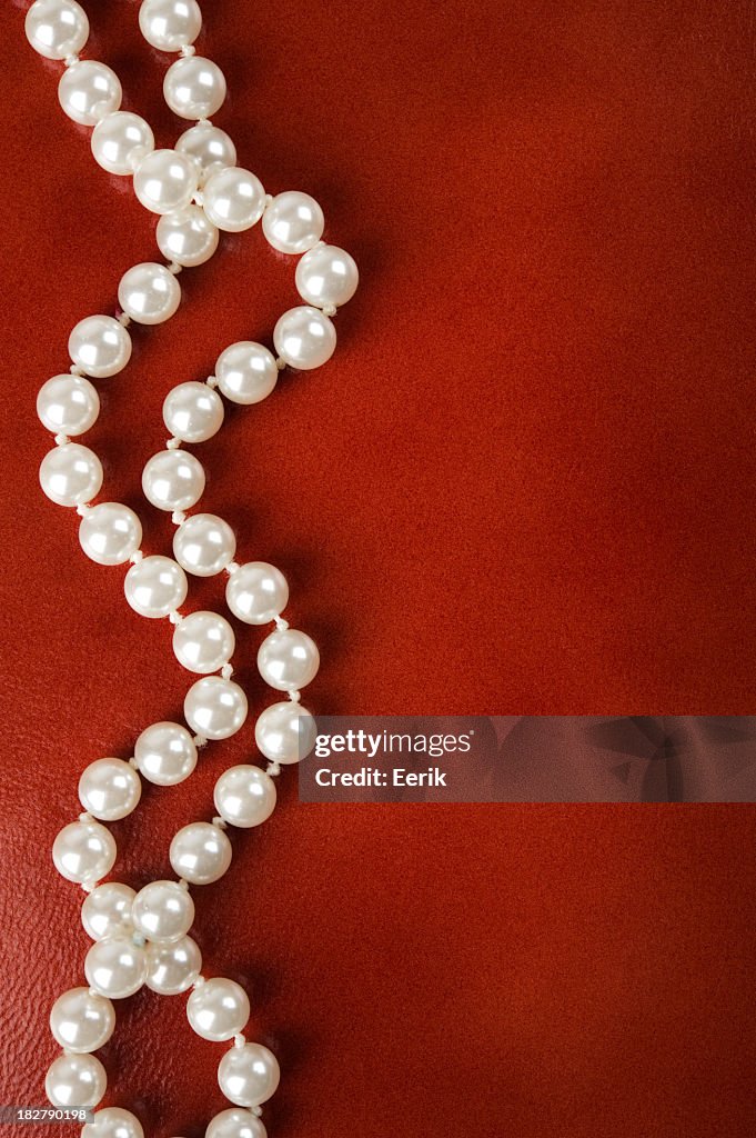 White pearl necklace on a red background