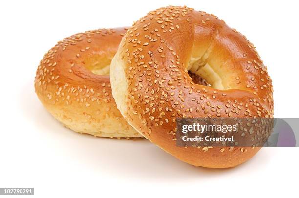 two sesame seed bagels isolated on white background - bagels stock pictures, royalty-free photos & images