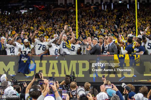 The Michigan Wolverines celebrate with the Big Ten Championship trophy after winning the Big Ten Championship against the Iowa Hawkeyes at Lucas Oil...