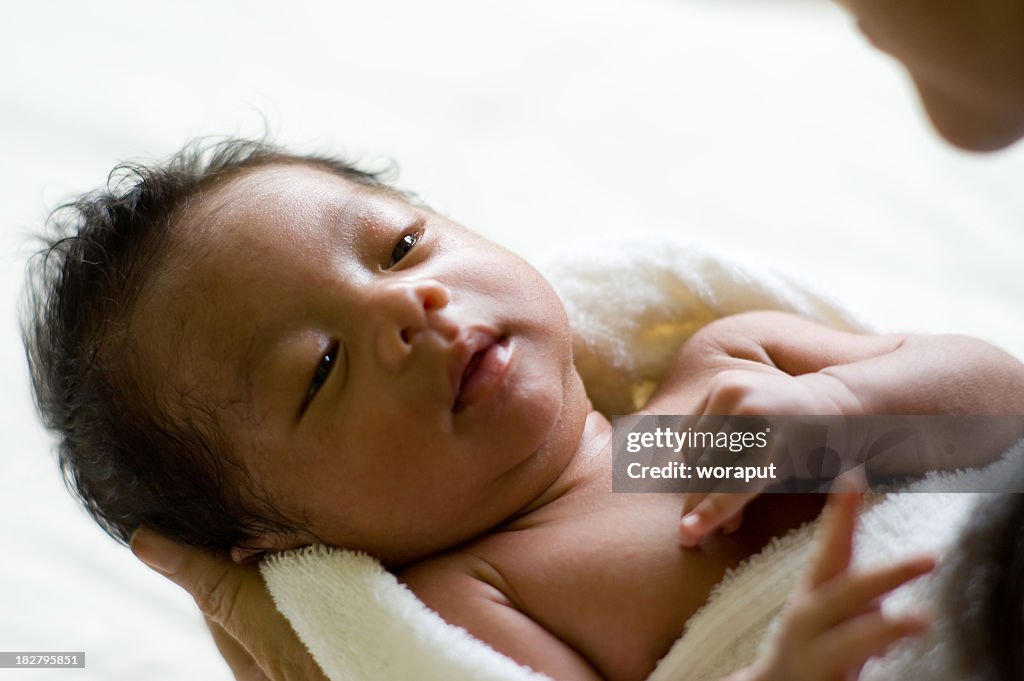 Close-up of a small baby wrapped in a blanket and being held