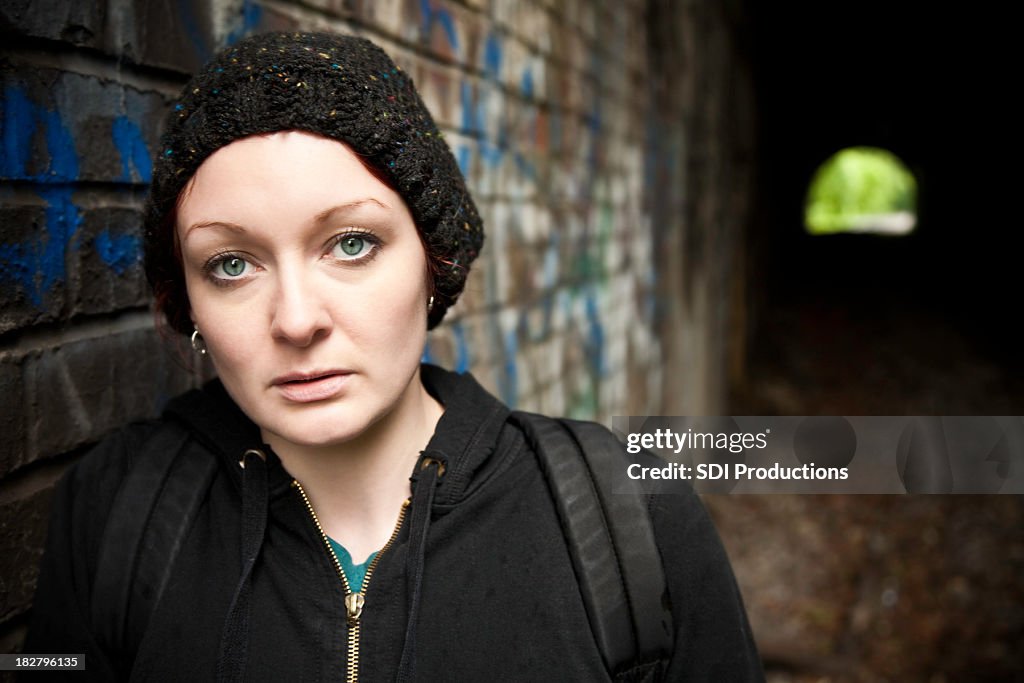 Serious Hooded Woman with Backpack in Tunnel