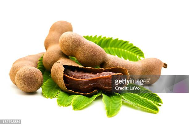 fresh tamarind one open on green leaves white back - tamarind stock pictures, royalty-free photos & images