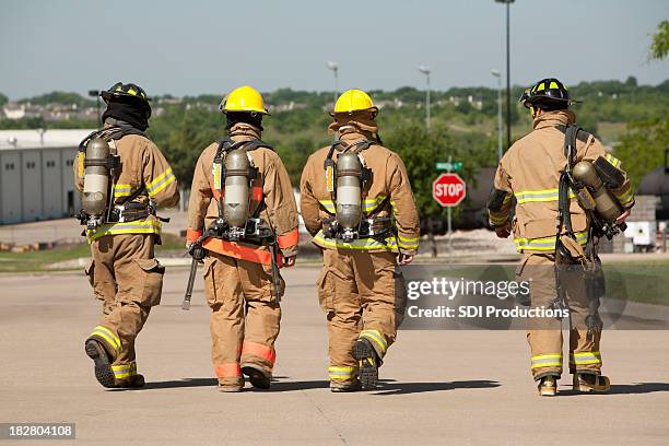 firefighters behind walking away from fire - firefighter stock pictures, royalty-free photos & images