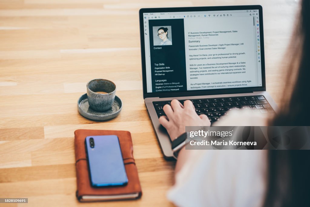 Young business woman searching for job online. Woman writing resume on laptop.