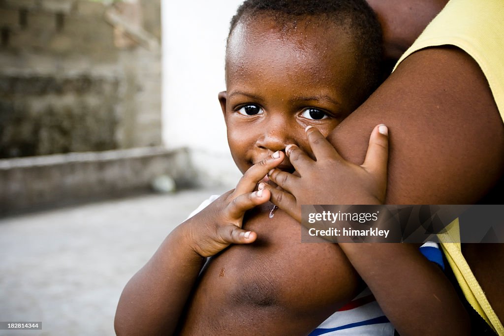 Small African baby boy embracing his mothers comforting arm