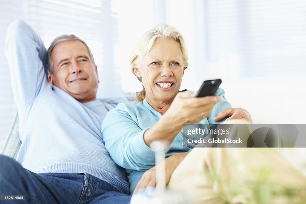 Retired couple watching TV while at home