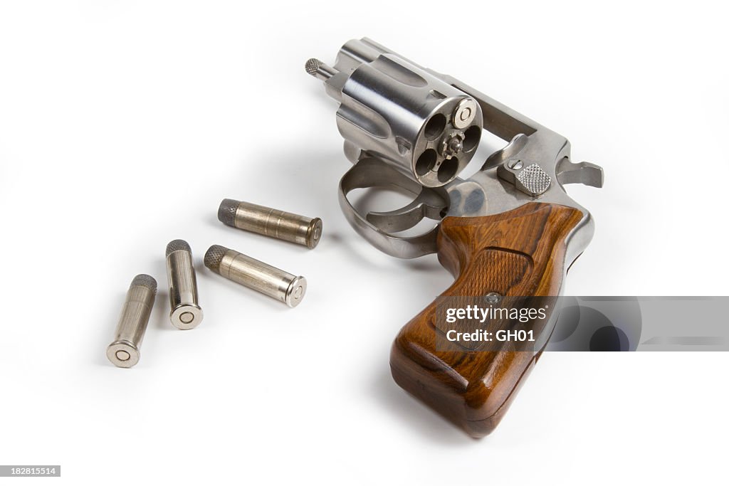 Revolver with bullets on white background