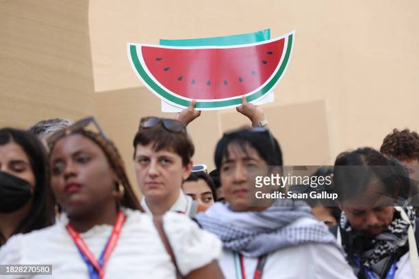 Activists, including one holding up a paper watermelon, a symbol of Palestine, protest for a ceasefire in the Gaza conflict on day four of the UNFCCC...