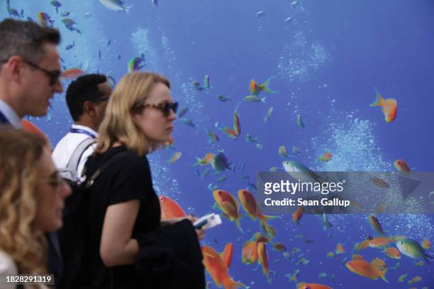 Participants walk past a billboard of ocean fish on day four of the UNFCCC COP28 Climate Conference at Expo City Dubai on December 03, 2023 in Dubai,...
