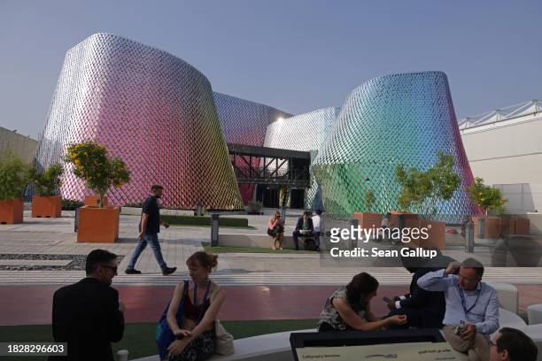 Participants sit near modern buildings on day four of the UNFCCC COP28 Climate Conference at Expo City Dubai on December 03, 2023 in Dubai, United...