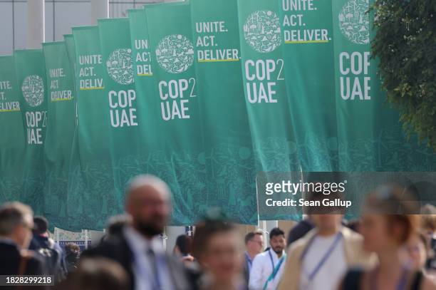 Participants walk by banners as they attend day four of the UNFCCC COP28 Climate Conference at Expo City Dubai on December 03, 2023 in Dubai, United...