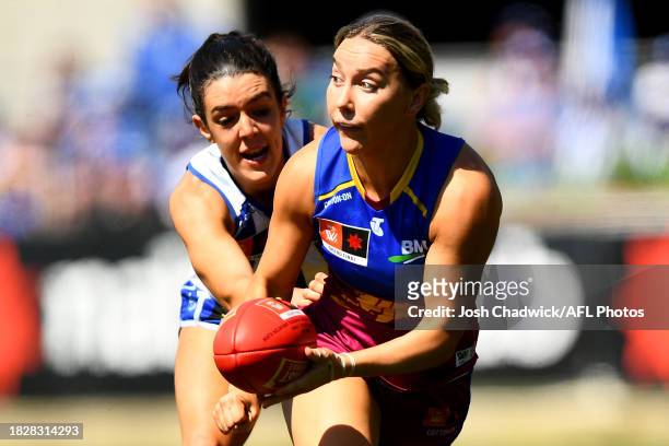 Jennifer Dunne of the Lions handballs whilst being tackled by Erika O'Shea of the Kangaroos during the AFLW Grand Final match between North Melbourne...