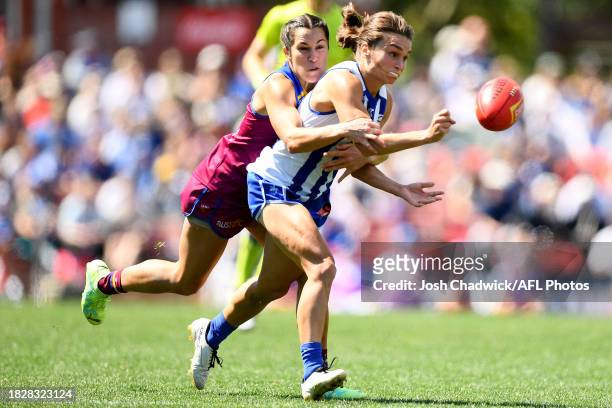 Ash Riddell of the Kangaroos handballs whilst being tackled by Ally Anderson of the Lions during the AFLW Grand Final match between North Melbourne...