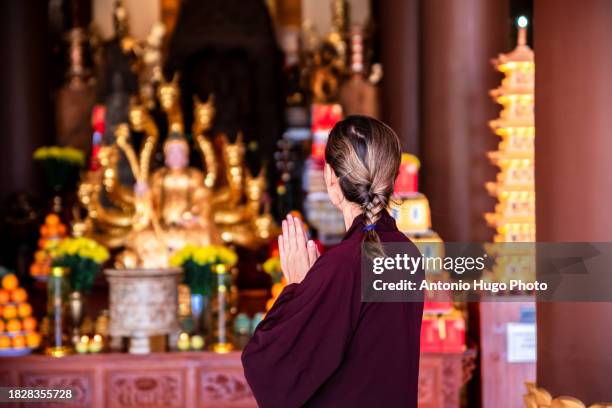 woman with a monk costume praying at the chua thien quang pagoda in mui ne city, vietnam. - god of wealth stock pictures, royalty-free photos & images