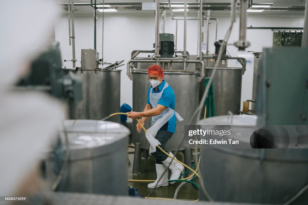 Factory worker cleaning flooring Factory interior storage tank section Filtering Machine and Tanks after production completed