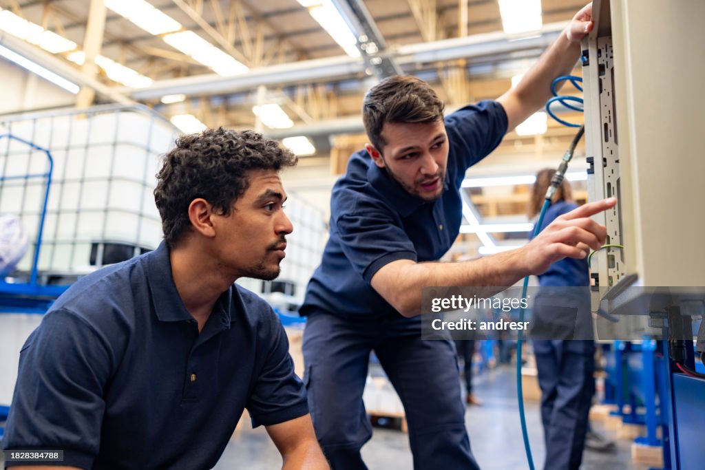 Team von Ingenieuren, die Maschinen in einer Fertigungsfabrik bedienen