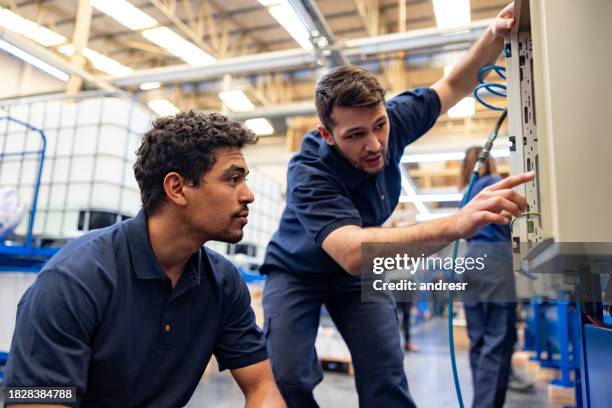team of engineers operating machines at a manufacturing factory - reparateur stockfoto's en -beelden