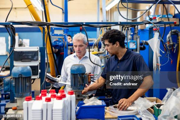 foreperson supervising the job of an employee at a water pump factory - production line stock pictures, royalty-free photos & images