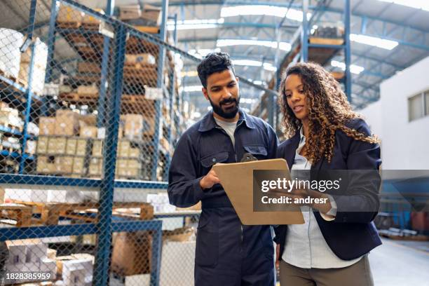 manager che parla con un dipendente in un capannone industriale - occupazione industriale foto e immagini stock