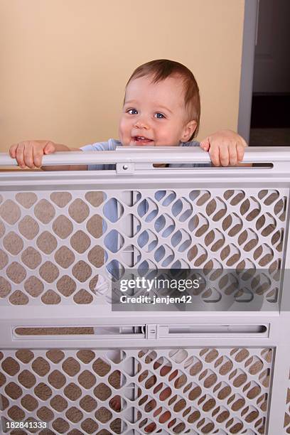 a happy smiling child over a child proofing fence - baby gate stock pictures, royalty-free photos & images