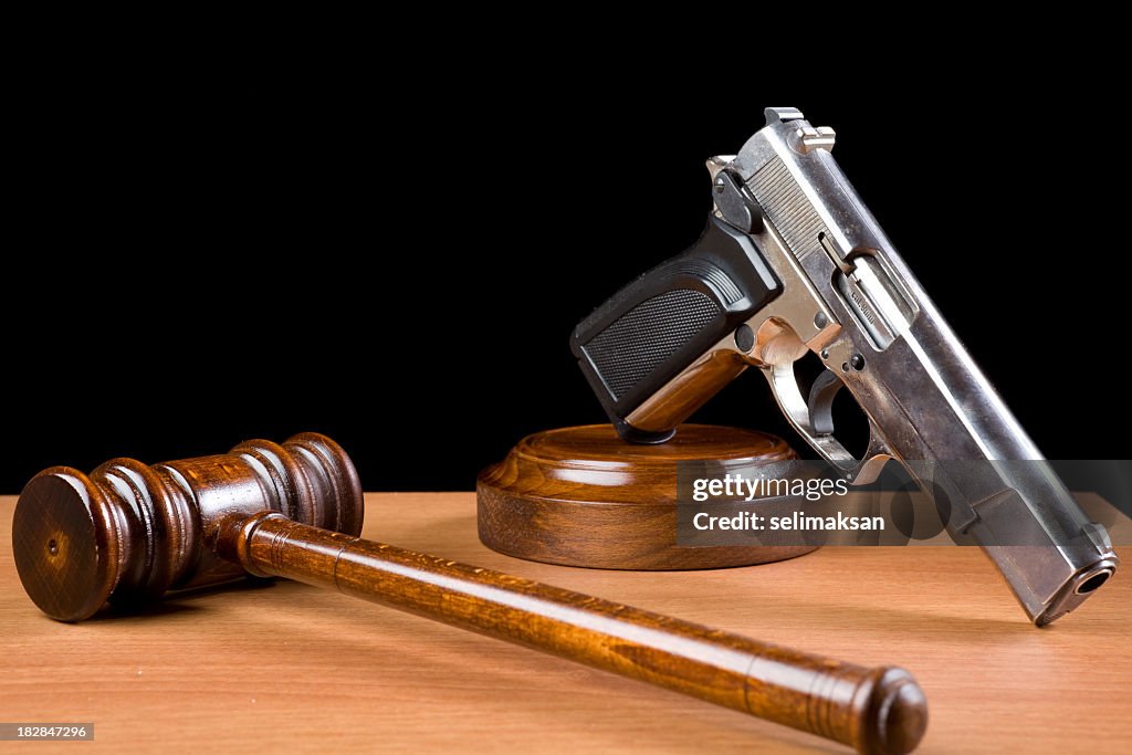 Hölzerne Richterhammer und die Pistole an einem Tisch für Crime Punishment Konzept