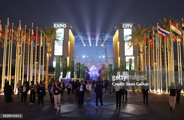 Participants walk among flagpoles on day four at night of the UNFCCC COP28 Climate Conference at Expo City Dubai on December 03, 2023 in Dubai,...