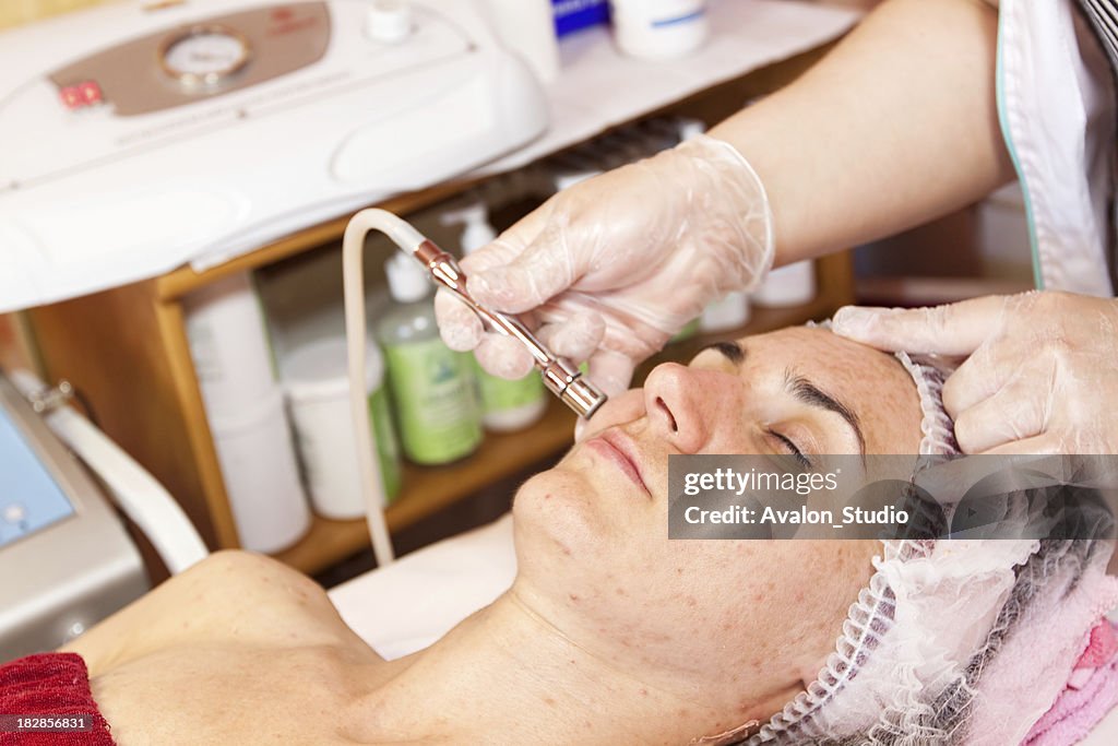 Beautician performs dermabrasion treatment on her face.