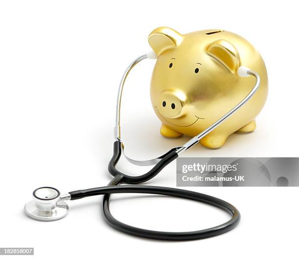 golden piggy moneybox with a black and metal stethoscope - stethoscope white background stock pictures, royalty-free photos & images