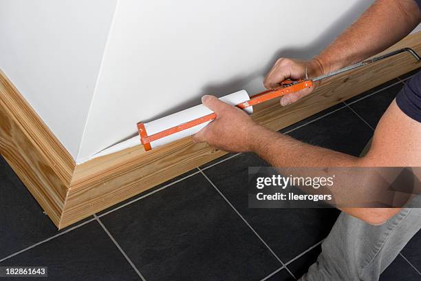 man caulking wooden skirting in a new property - finale 個照片及圖片檔