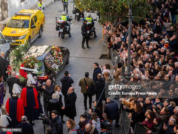 Decenas de personas observan la salida del coche funebre hacia el cementerio tras el funeral de la actriz Concha Velasco, en la Catedral de Nuestra...