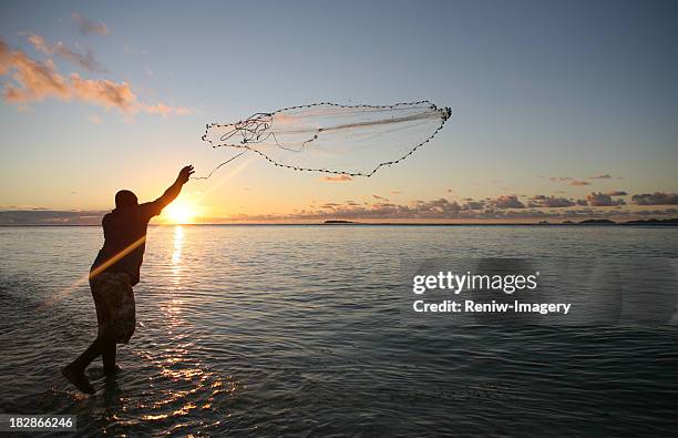fisherman casting his net at sunset - kommersiellt fisknät bildbanksfoton och bilder