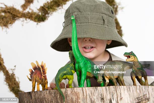 young boy wearing safari outfit playing with toy dinosaurs  - dino stock pictures, royalty-free photos & images