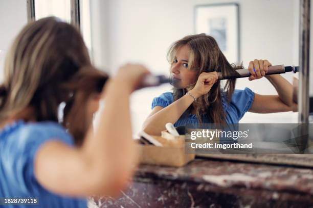 teenage girl, wearing a regency era dress, is making hairstyle with a hair iron - iron appliance stock pictures, royalty-free photos & images