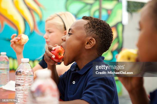 students during lunch break. - child eating a fruit stockfoto's en -beelden