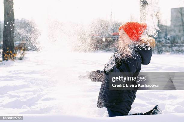 11-year-old boy in a red hat and blue jacket throws snow and enjoys winter in the park,copy space - kazan stock pictures, royalty-free photos & images