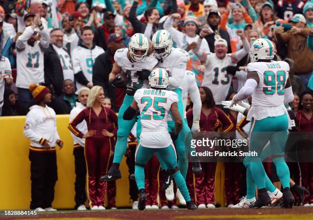 Andrew Van Ginkel of the Miami Dolphins celebrates with teammates after returning an interception for a touchdown against the Washington Commanders...