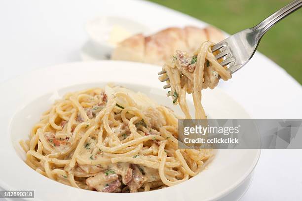 a fork spindles from a bowl of linguine carbonara  - romano stock pictures, royalty-free photos & images