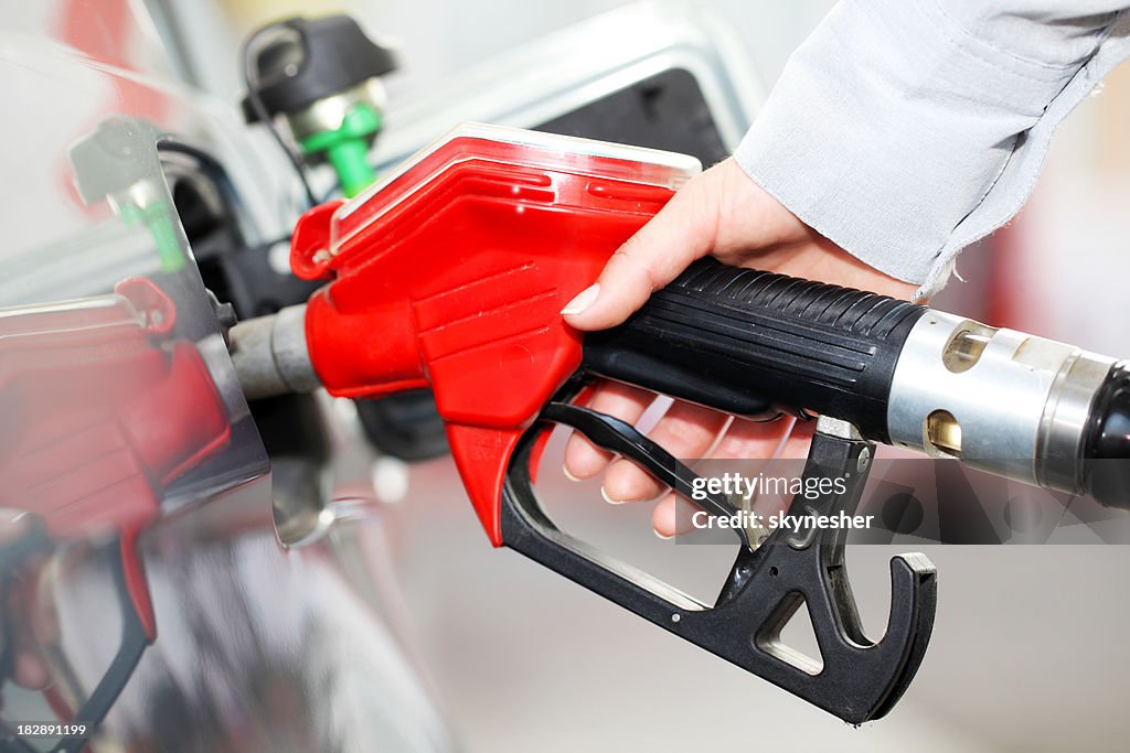 Person refueling a car at gas station.