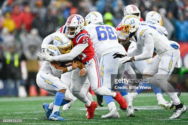 Austin Ekeler of the Los Angeles Chargers runs with the ball while being tackled by Josh Uche of the New England Patriots in the second quarter at...