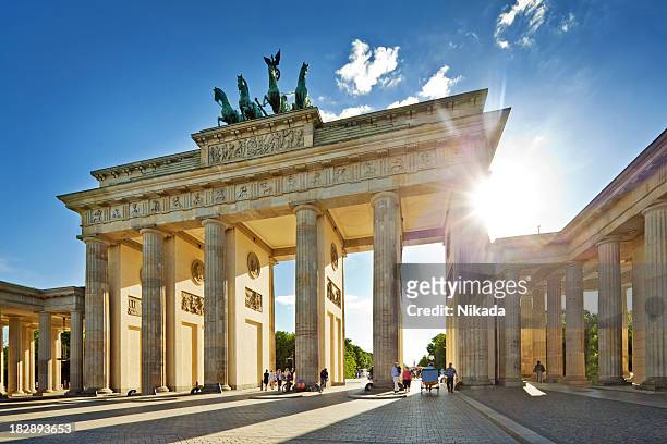 sol brilhando através do portão de brandemburgo, em berlim - brandenburg gate - fotografias e filmes do acervo