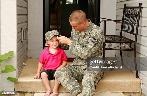 a military styled father letting his son try on his hat - fighter pilot stock pictures, royalty-free photos & images