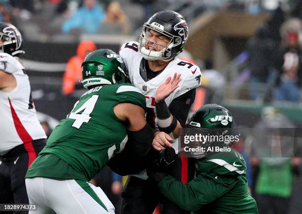 Desmond Ridder of the Atlanta Falcons is tackled by Jermaine Johnson and Solomon Thomas of the New York Jets during the second quarter at MetLife...