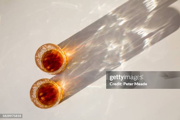 the sun shining on two glasses of whisky and throwing long shadows - crystal glassware stock pictures, royalty-free photos & images