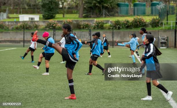 young female soccer players doing stretching workout during training session on field - south africa training session stock pictures, royalty-free photos & images