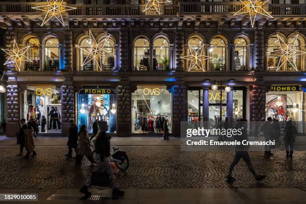 People stroll past an OVS flagship store, decorated with Christmas star - shaped lights, in Via Dante on December 03, 2023 in Milan, Italy.