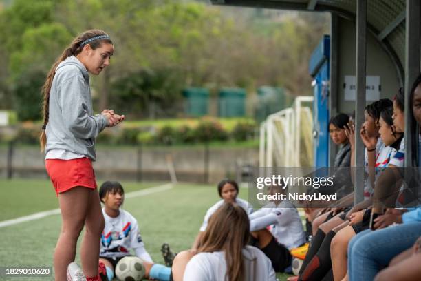 woman coach explaining game plan to young female players on field after warm up session - south africa training session stock pictures, royalty-free photos & images