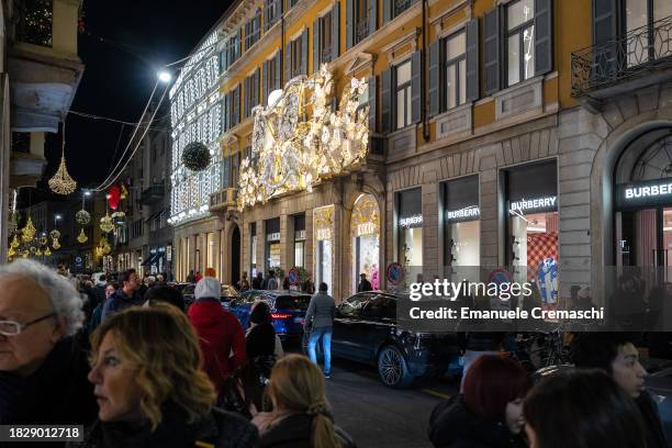 People walk past the French multinational luxury fashion house Christian Dior flaghsip store, whose facade is richly decorated with Christmas lights,...