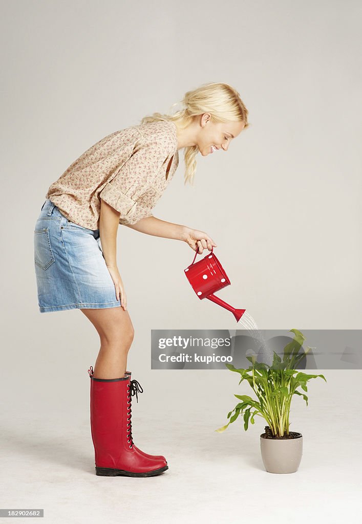 Young woman using watering can to water plant