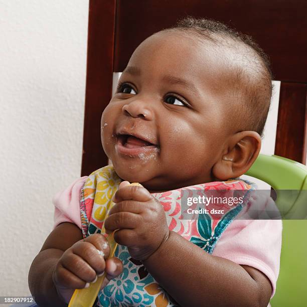 baby girl eating with spoon - baby eating yogurt stockfoto's en -beelden