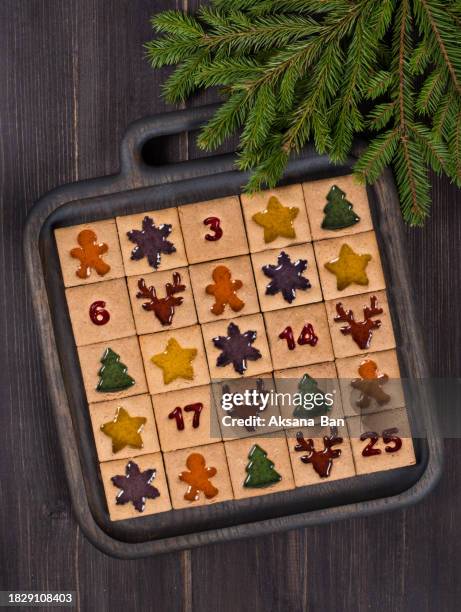 christmas  cookies. advent calendar. gingerbread cookies with multi-colored marmalade filling in the form of gingerman, stars, christmas trees, snowflakes, deer heads, numbers. on a wooden plate. decorated with tree branches. dark wooden background. top v - rustic star stock pictures, royalty-free photos & images